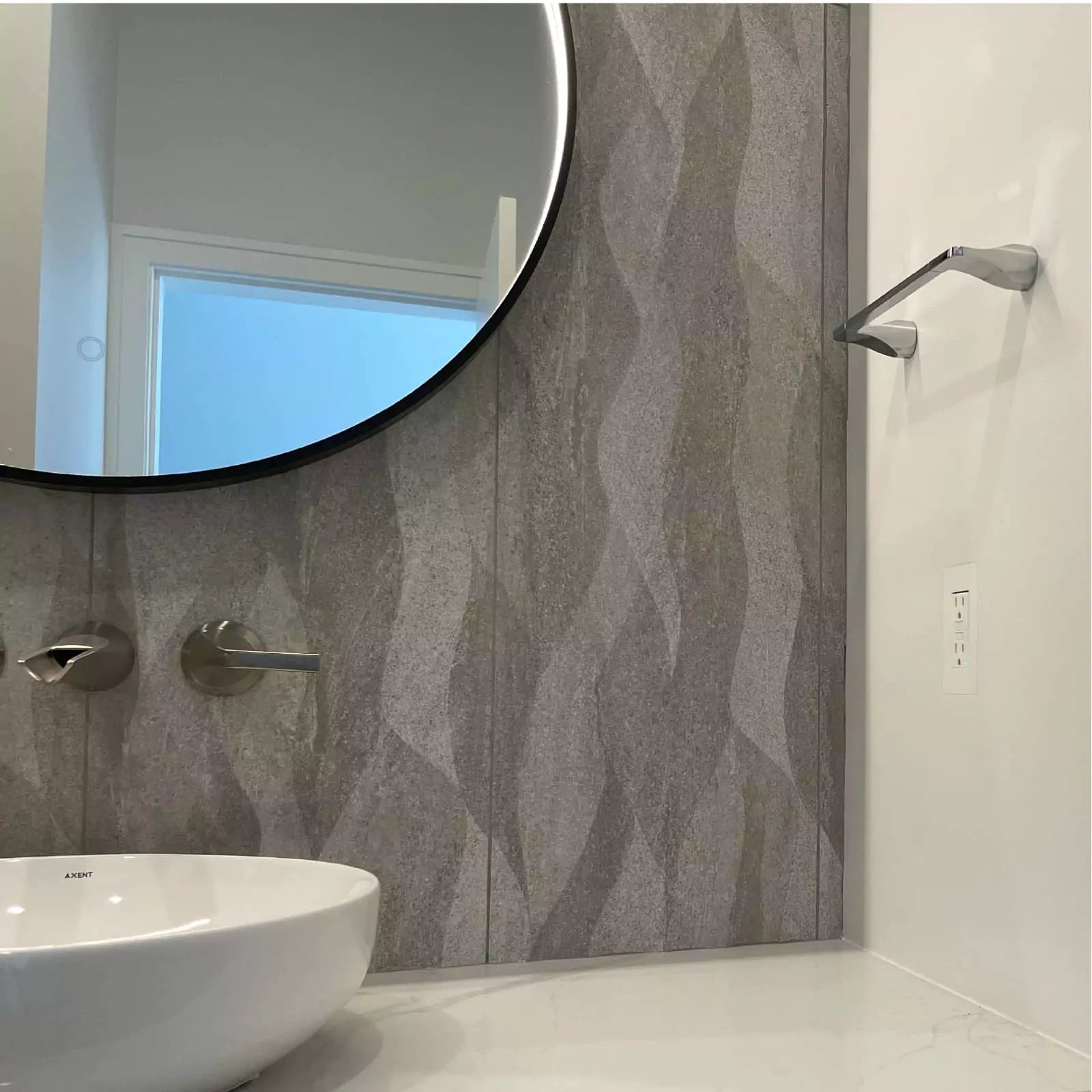 Flush-mounted GFCI outlet using CONCEAL beside a wall-mounted faucet, vessel sink and round mirror in a modern bathroom.
