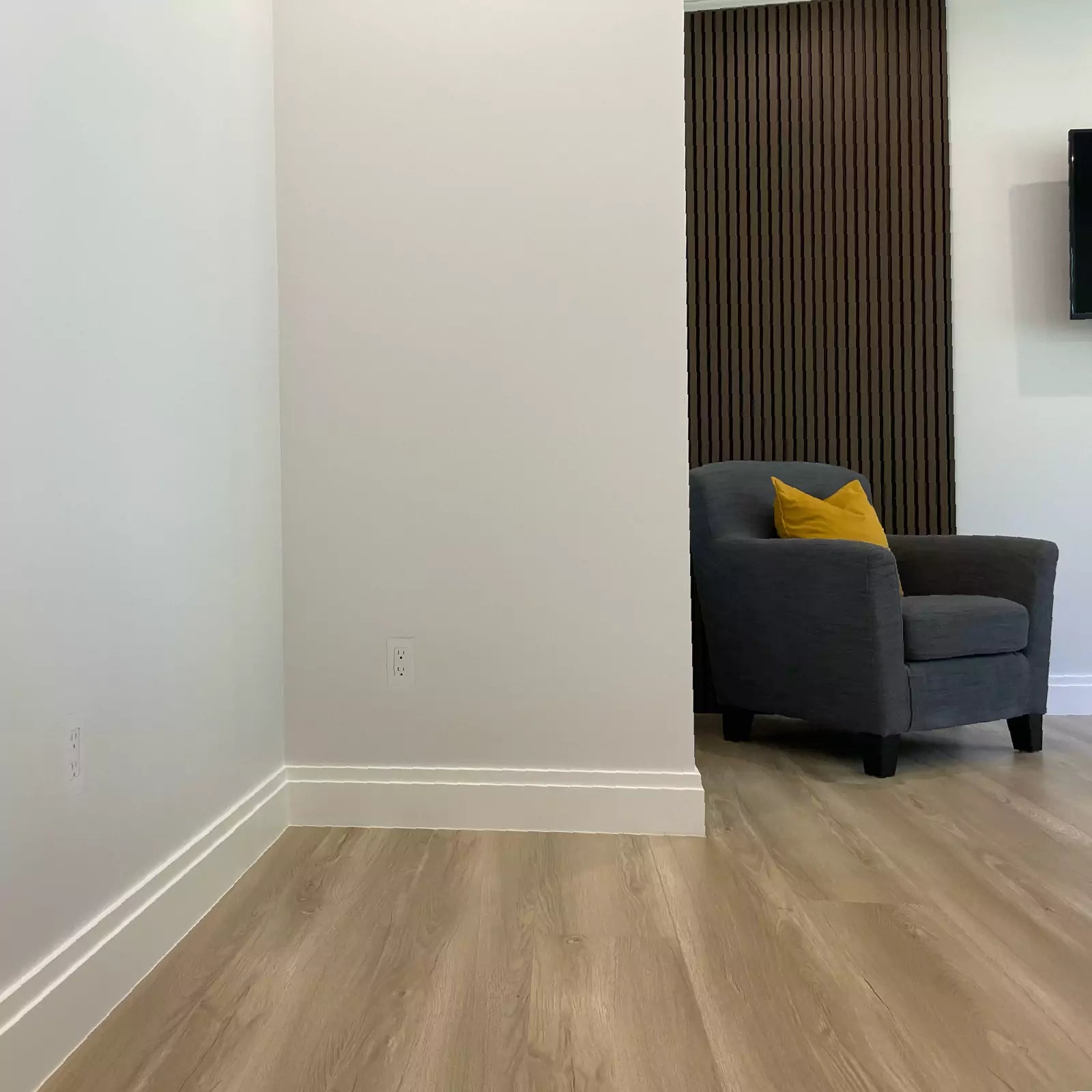 Gray armchair with a yellow pillow in a room with wooden floors and white walls with CONCEAL flush-mounted outlets installed