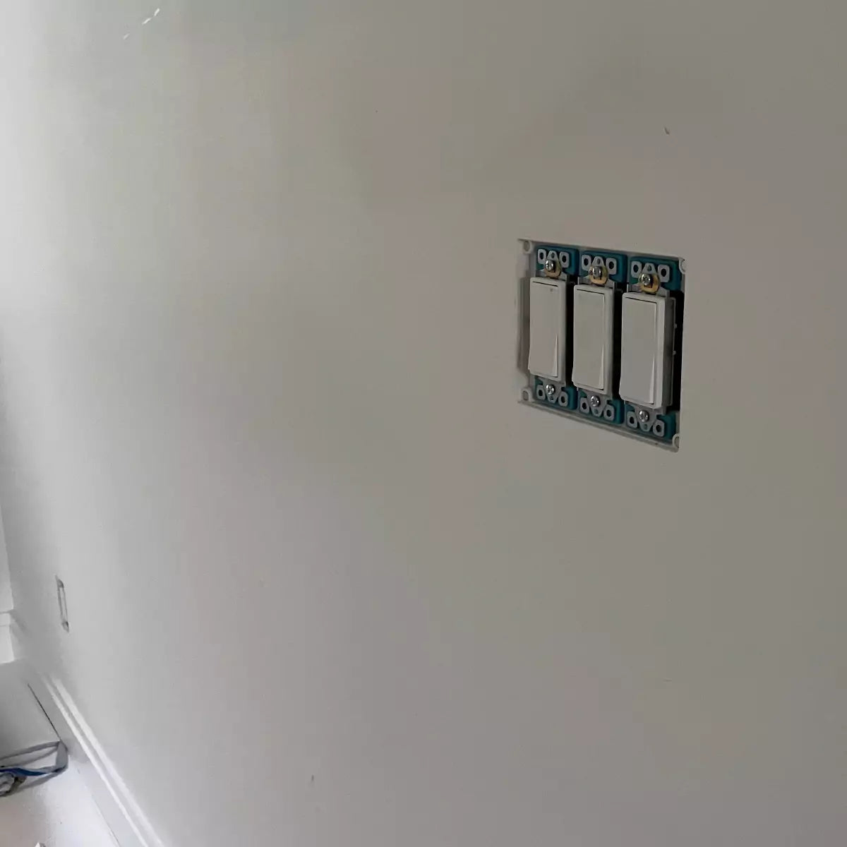Three Decora light switches flush-mounted in a white wall using a 3-gang CONCEAL system with cover plate not yet installed