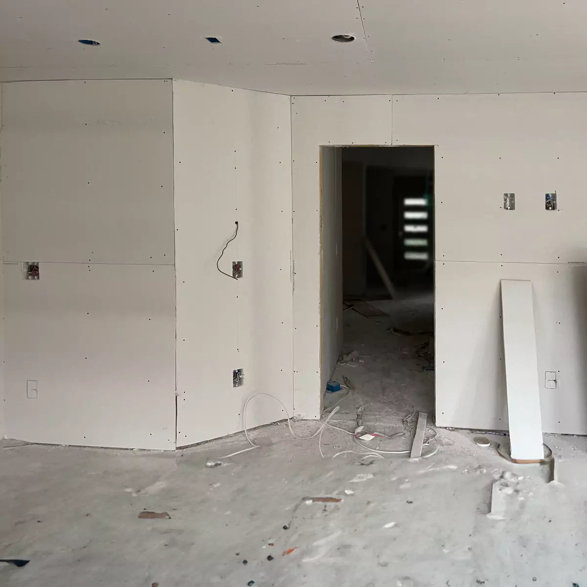 Unfinshed room with drywall sheets hung and openings cut in preparation for CONCEAL mud rings installation
