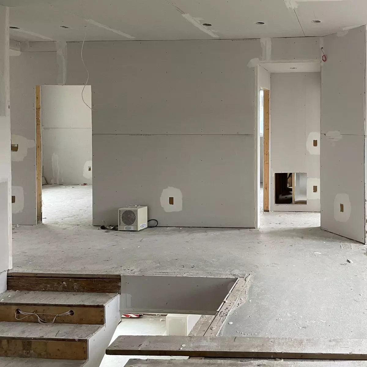 Unfinshed room with drywall sheets hung, CONCEAL mud rings installed and drywall mudding in progress