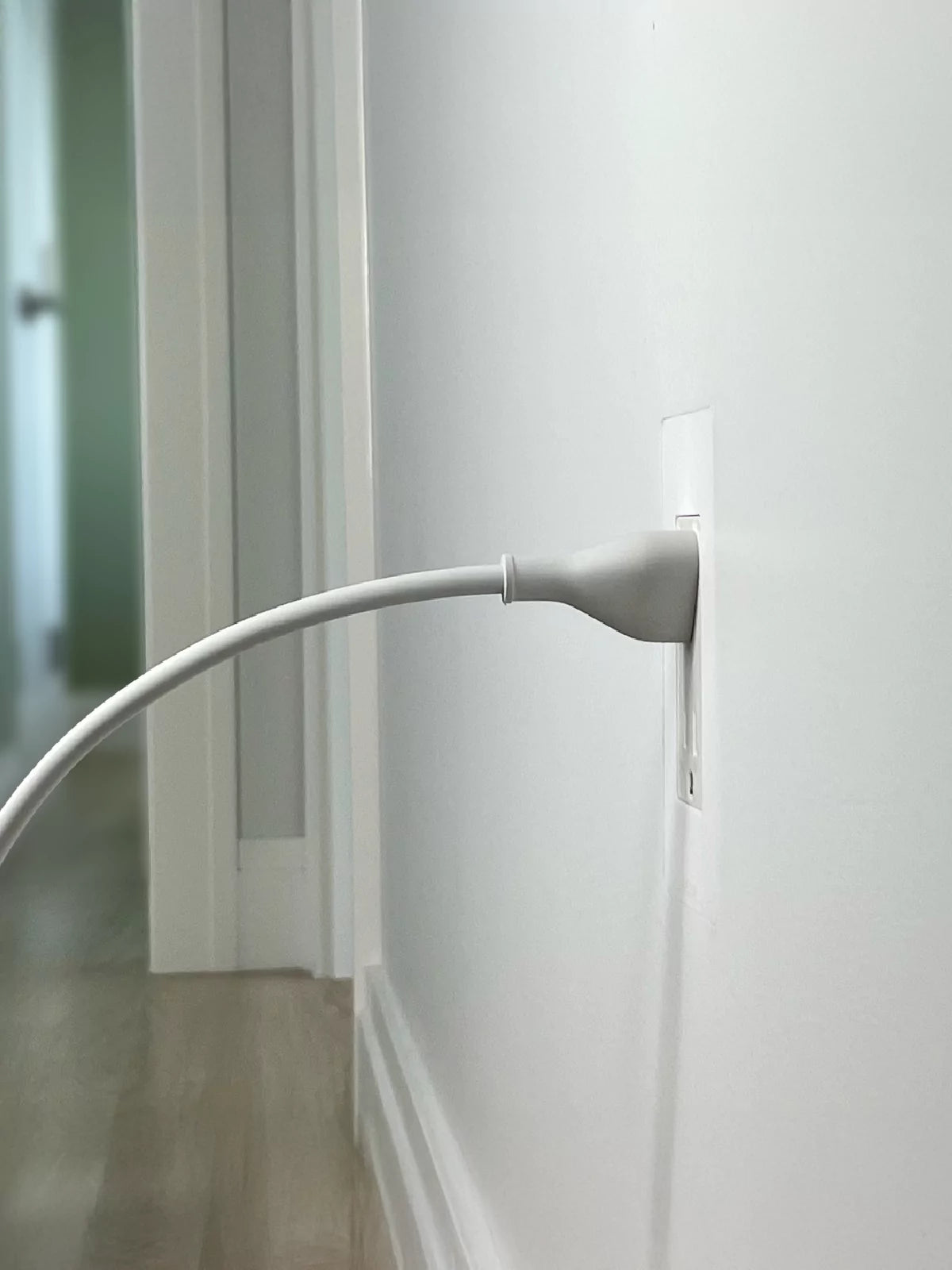 Discreet trimless outlet, flush with hallway wall surface, cord plugged in, demonstrating CONCEAL flush-mounting system