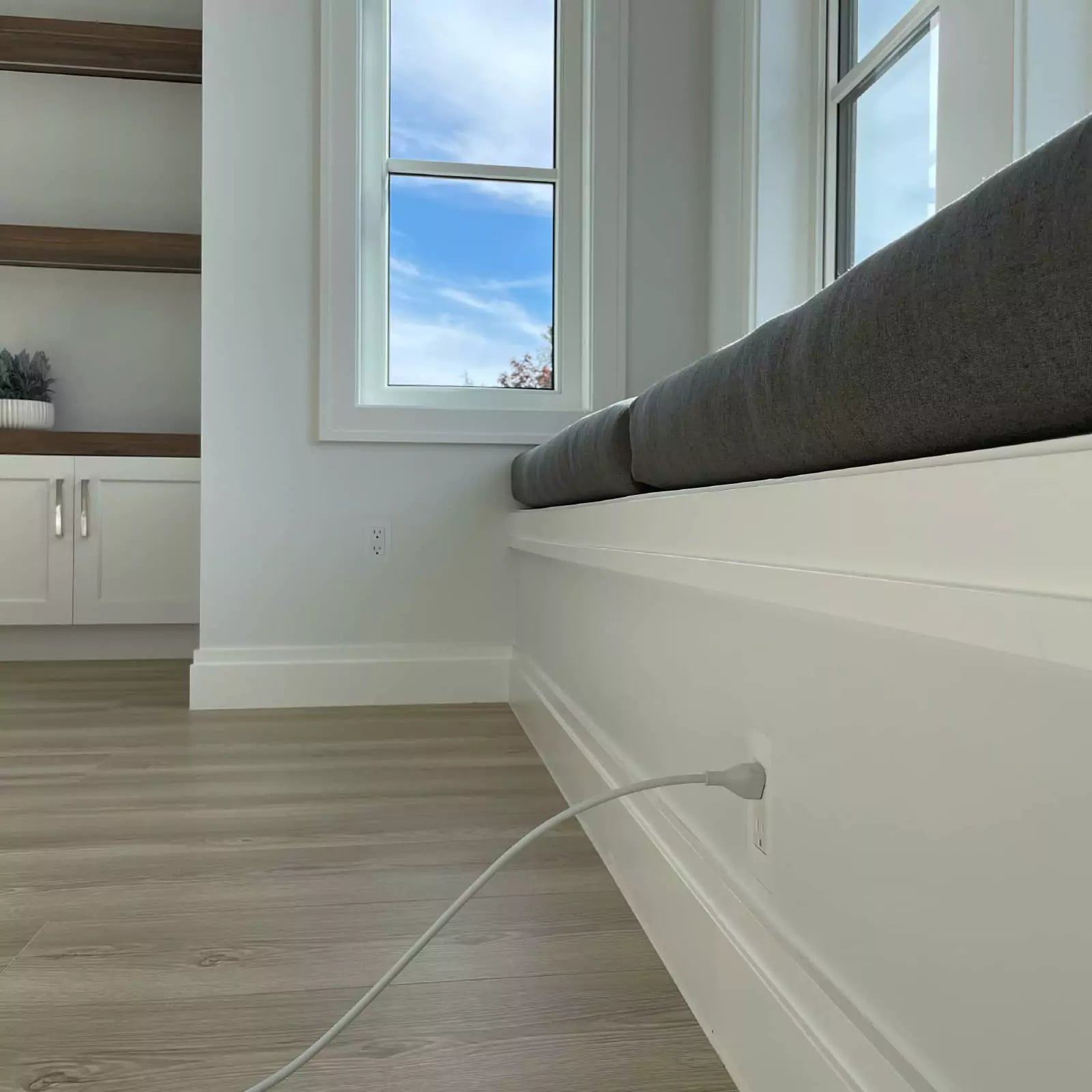 Window seat with cushions in a modern living room with large windows and two 1-gang CONCEAL flush-mounted outlets visible