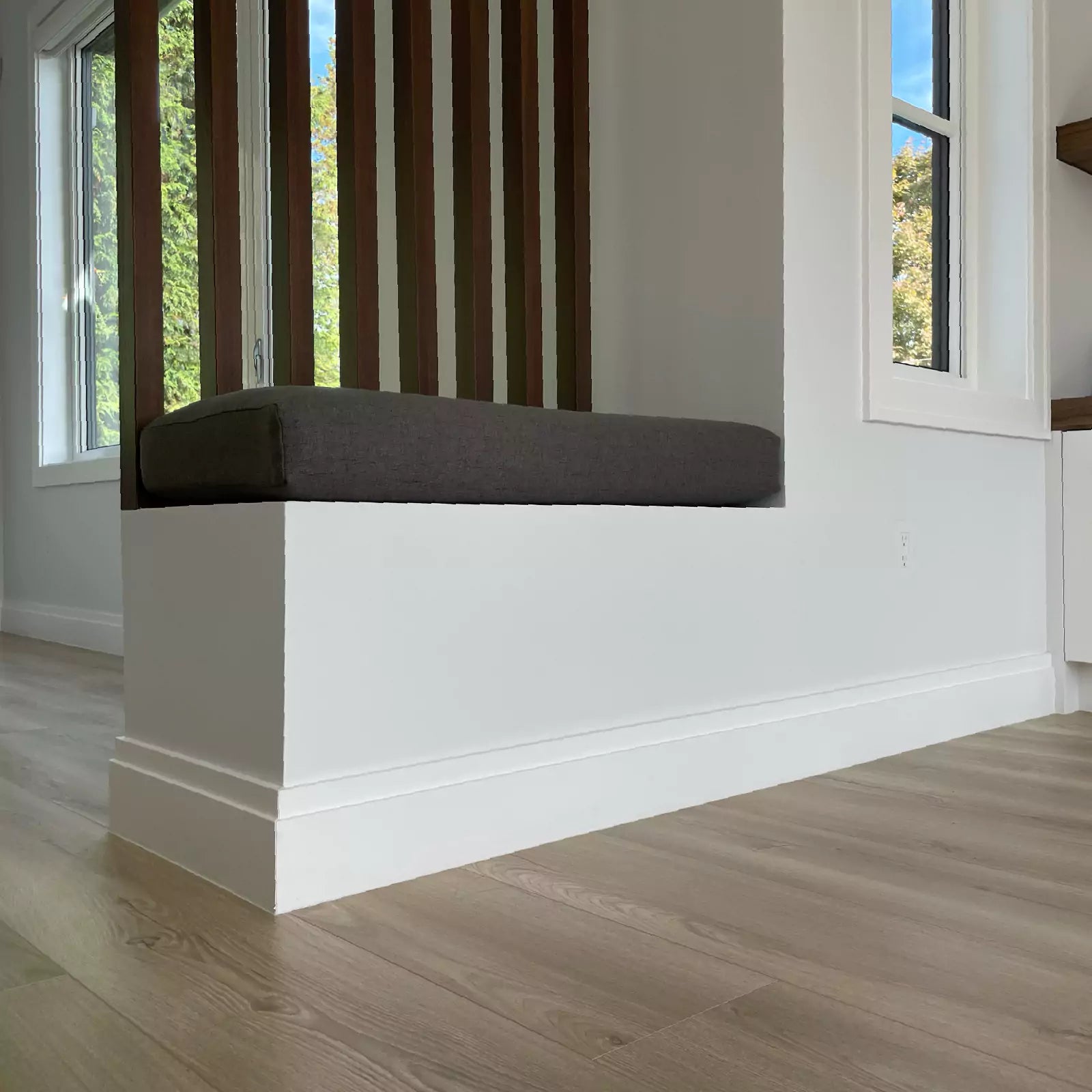 Cushioned seat in front of a wood slat wall with a CONCEAL flush-mounted outlet underneath a window