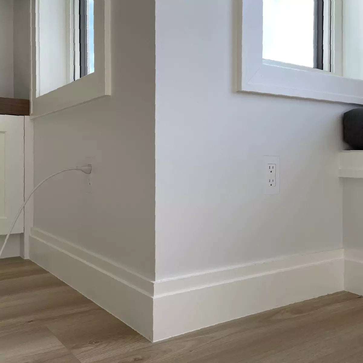 Two 1-gang flush-mounted Decora electrical outlets on a white wall with a white power cord plugged into one of the outlets