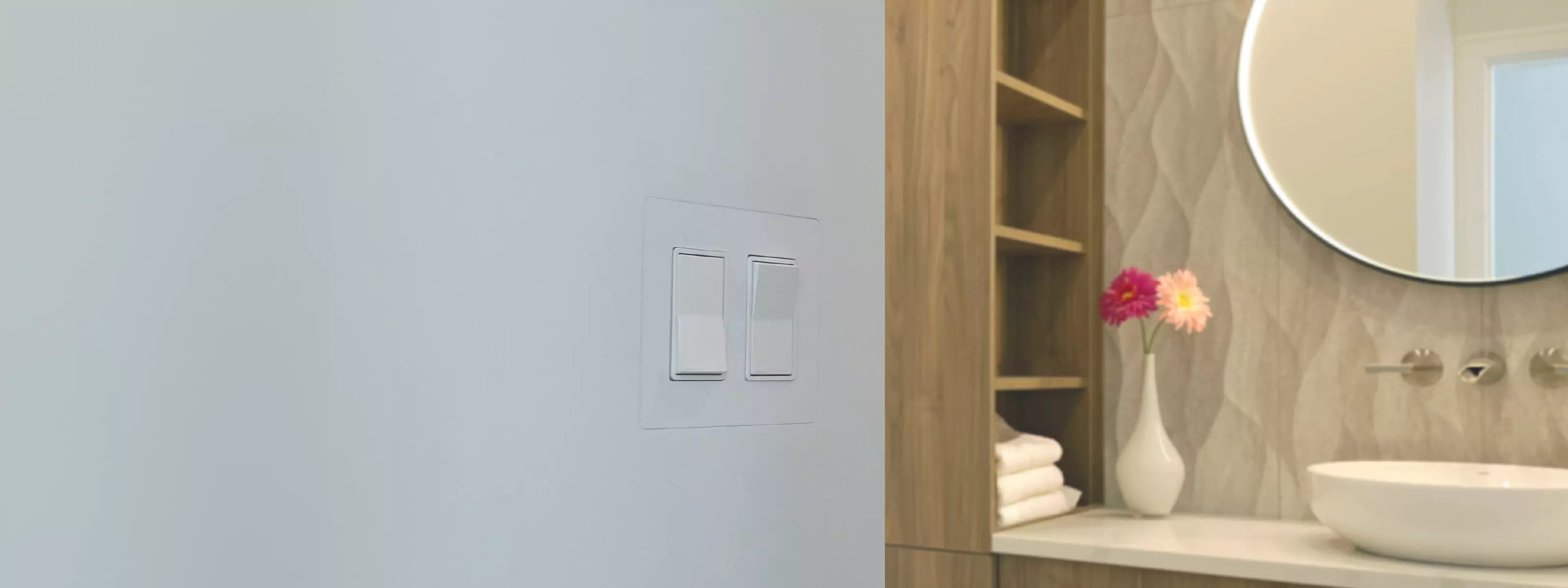 Two light switches flush-mounted using CONCEAL, seamlessly blending into the wall beside a modern vanity and round mirror