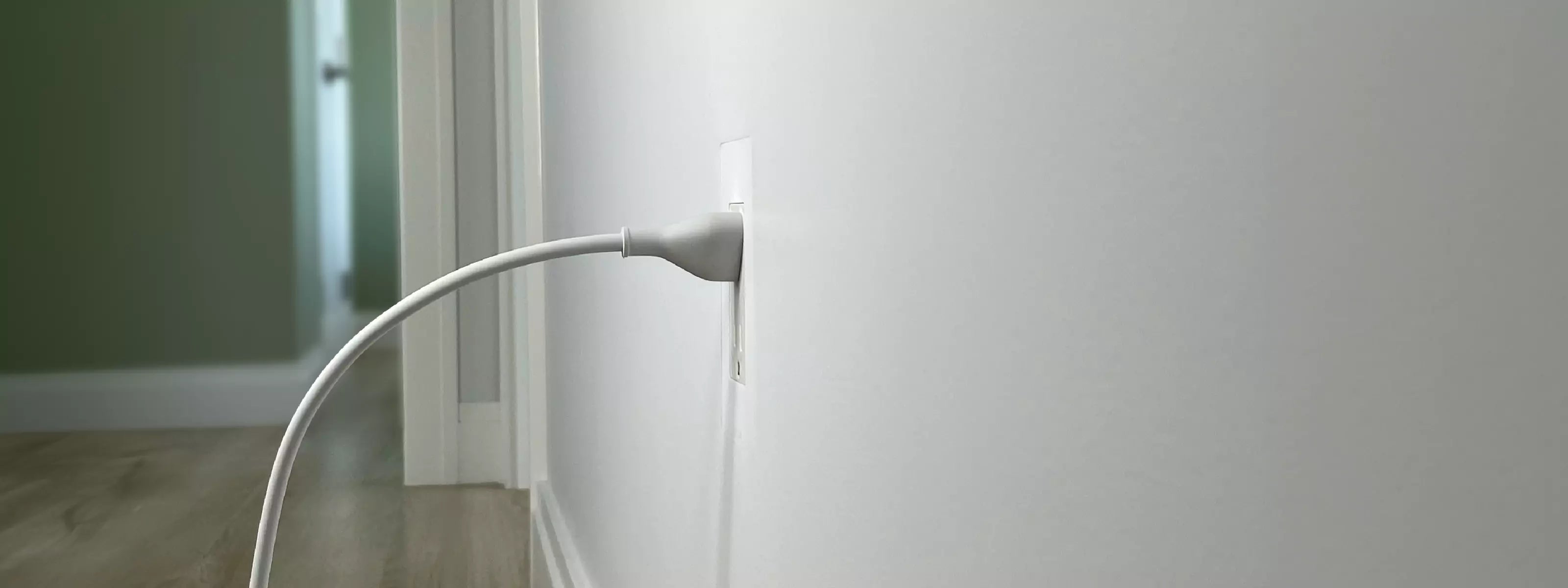 Discreet trimless outlet, flush with hallway wall surface, cord plugged in, demonstrating CONCEAL flush-mounting system