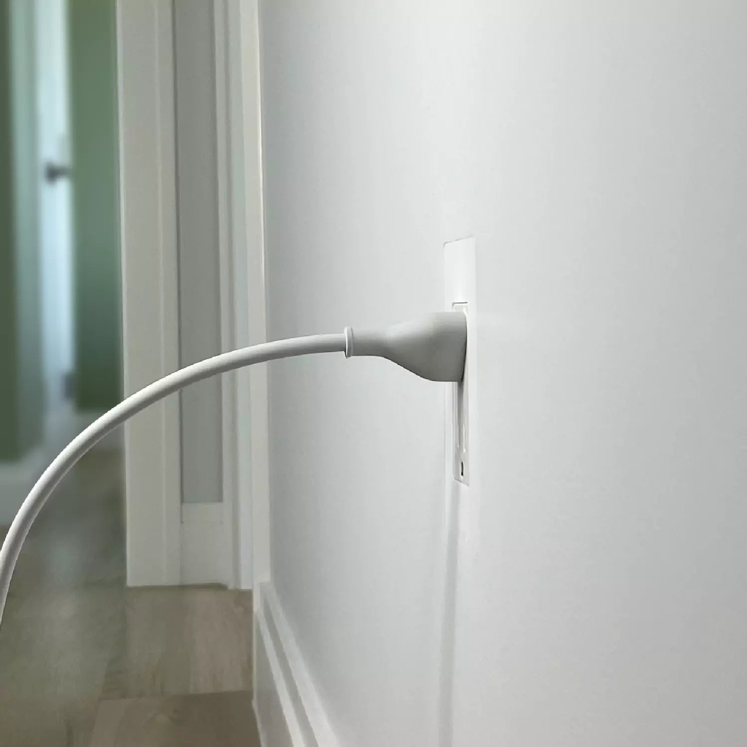 Discreet trimless outlet, flush with hallway wall surface, cord plugged in, demonstrating CONCEAL flush-mounting system
