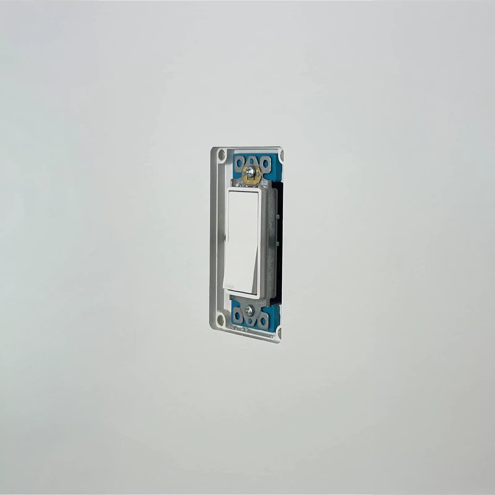 CONCEAL flush-mounted Decora light switch on a white wall before the magnetic wall plate is attached.